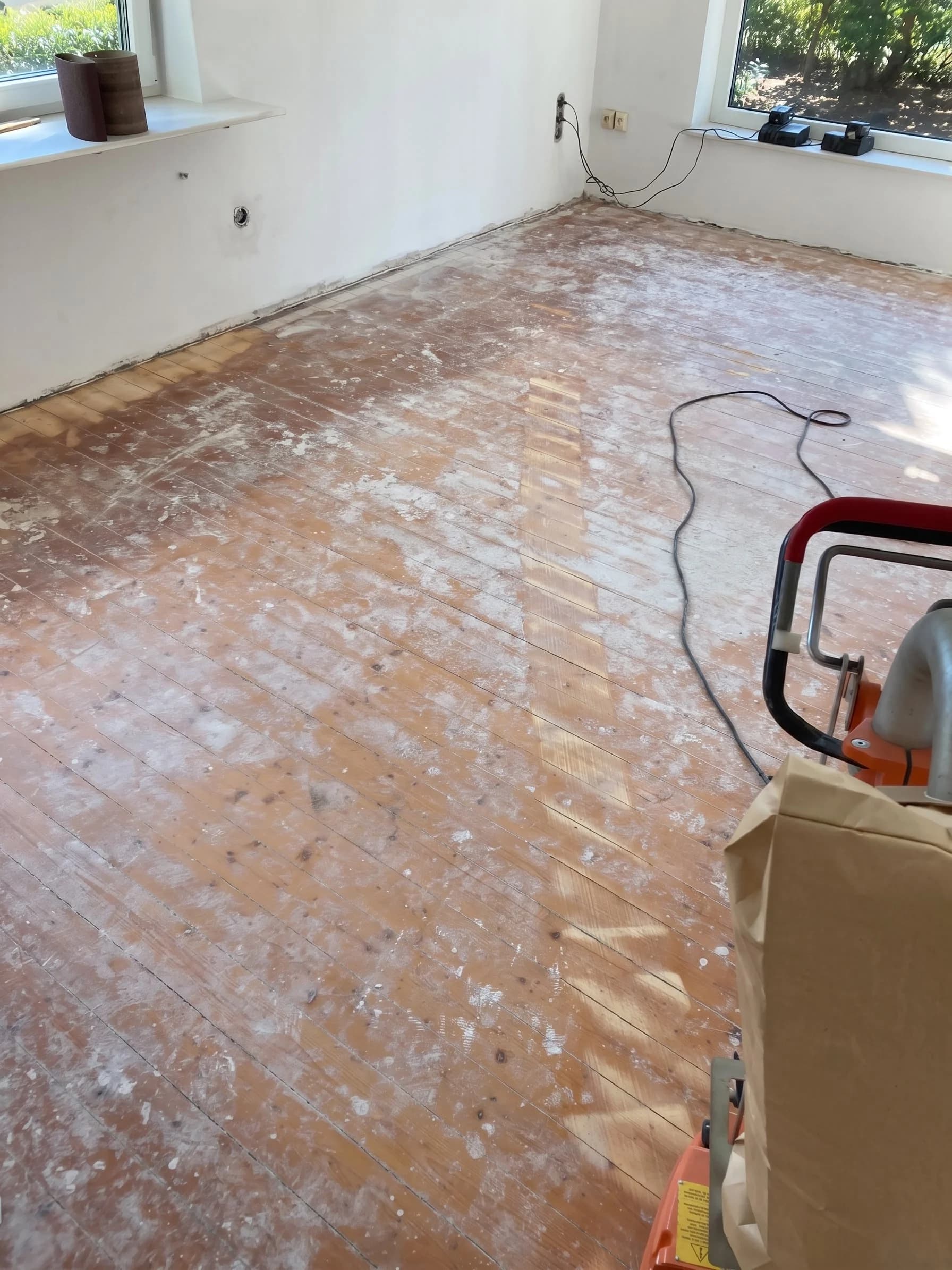 Alter Dielenboden mit Farbresten und Spachtelspuren vor der Sanierung