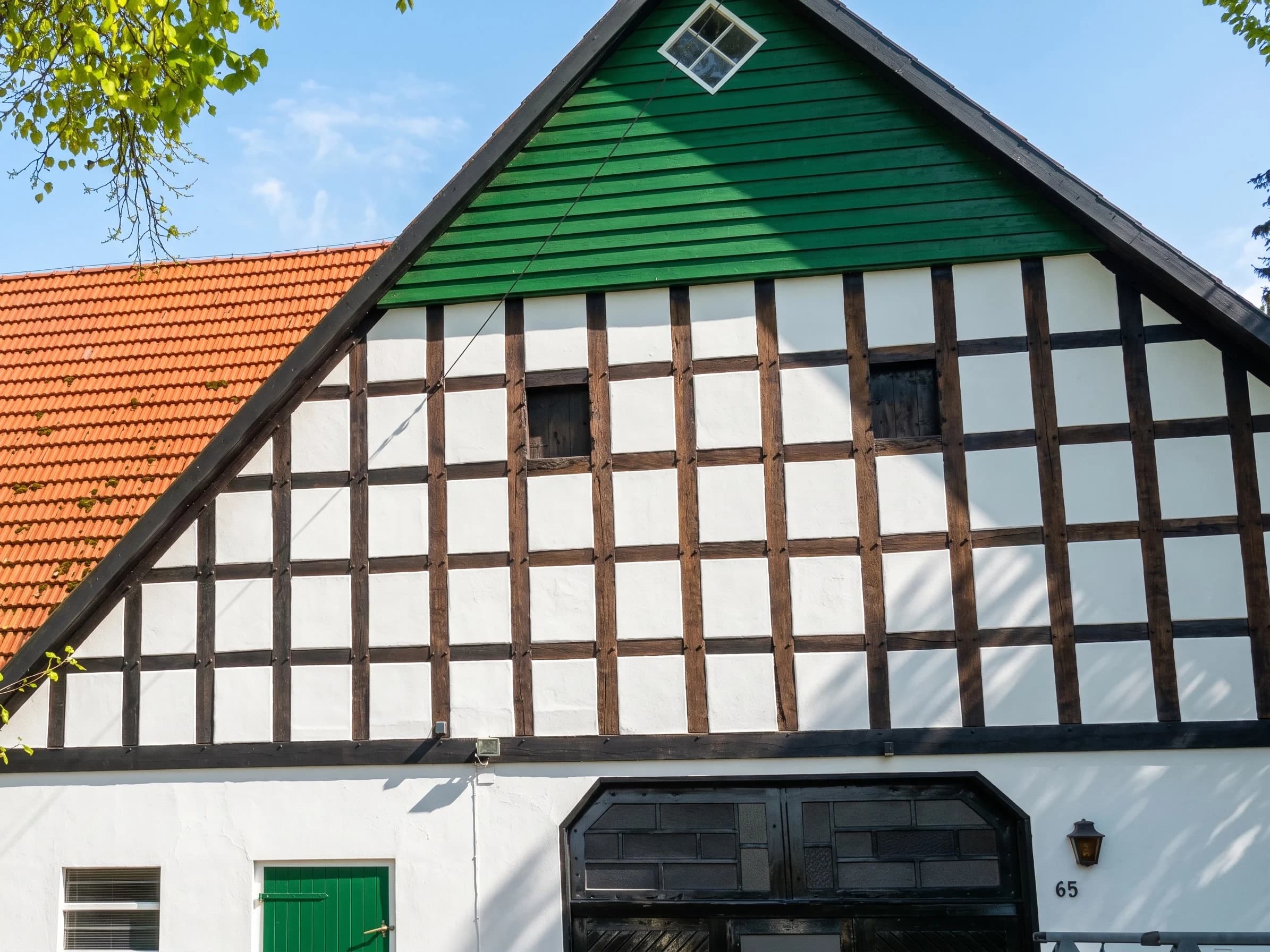 Frisch gestrichener Fachwerkgiebel in Weiß, Schwarz und Grün nach der Sanierung