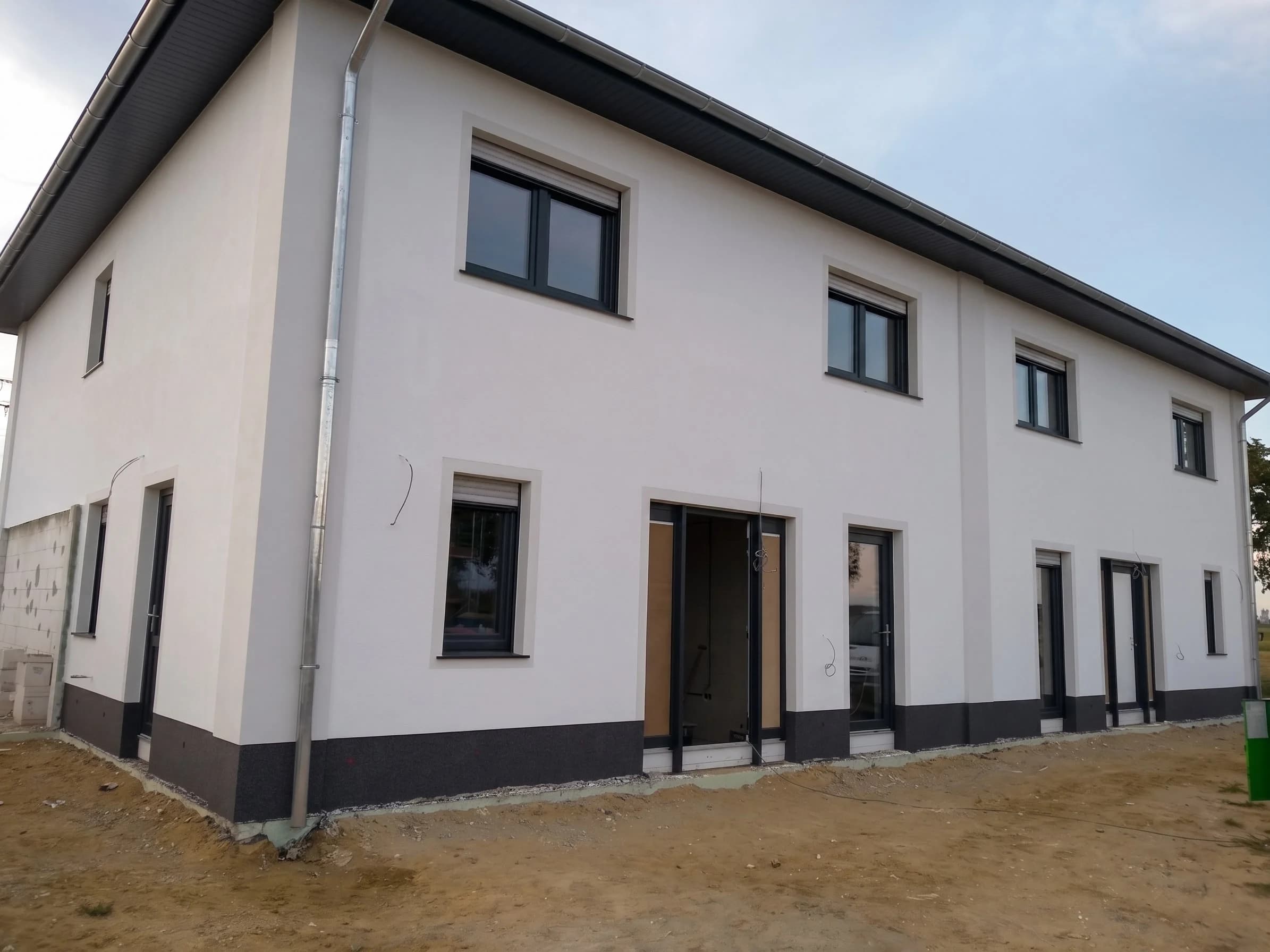 Frisch gestrichenes Wohnhaus mit weißer Fassade und dunklem Dach