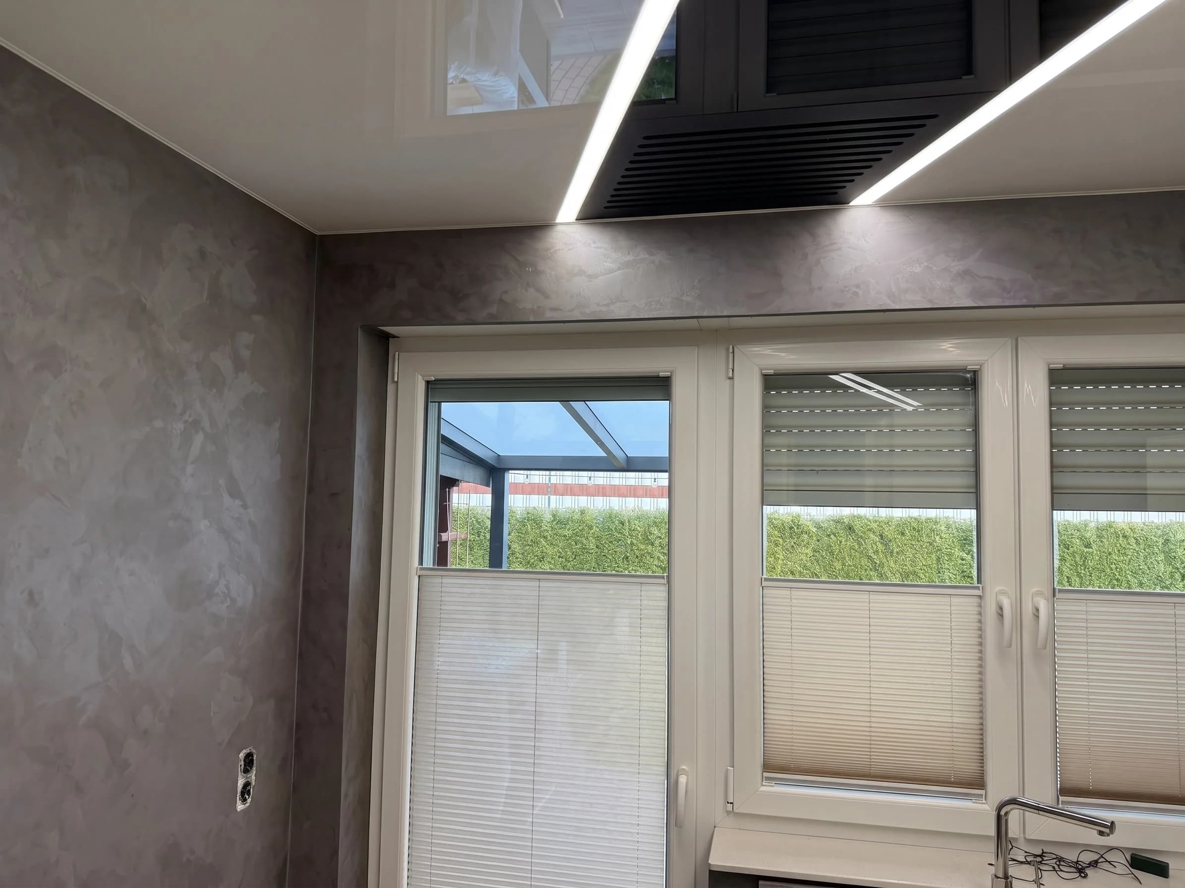 Graue Spachteltechnik-Wand neben Glanzdecke mit Lichtprofilen