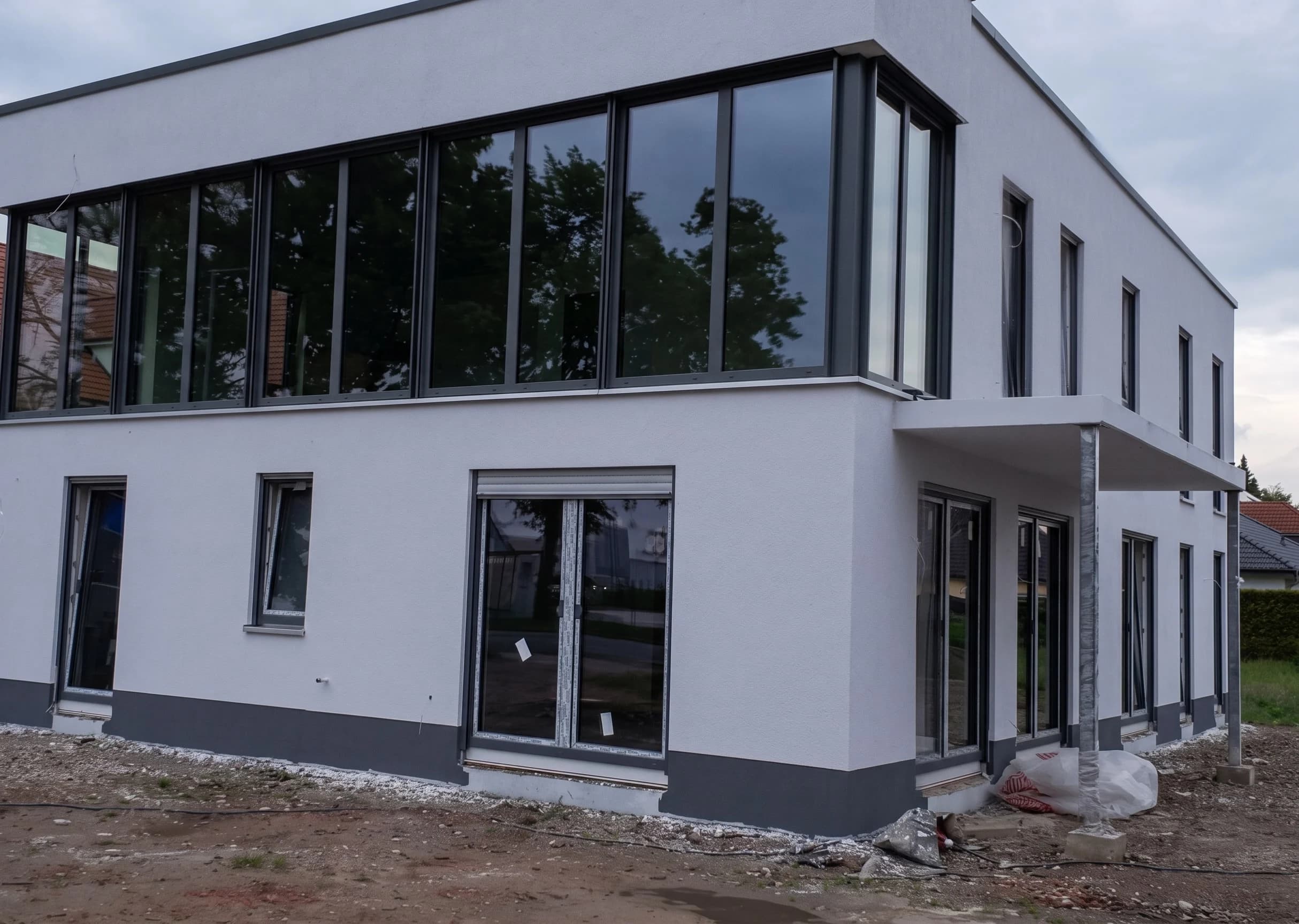 Modernes Flachdachgebäude mit heller Fassade und dunkler Fensterfront
